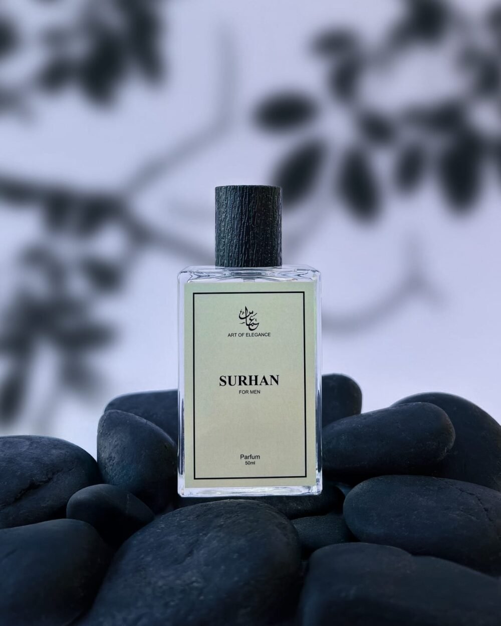 Clear glass bottle of "Surhan for Men" perfume placed on smooth black stones with a blurred leaf-pattern background.