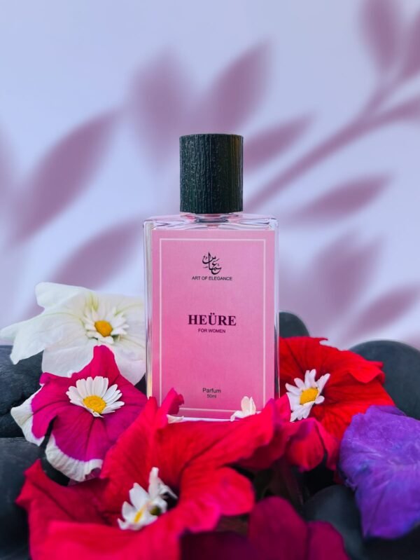 Pink bottle of “Heüre for Women” perfume by Art of Elegance, placed among vibrant flowers with a soft lavender leaf-shadowed background