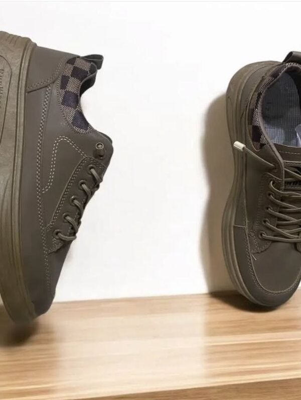 A pair of olive brown casual sneakers displayed creatively on a wooden platform with one shoe mounted vertically and the other placed upright, featuring check-patterned ankle lining.