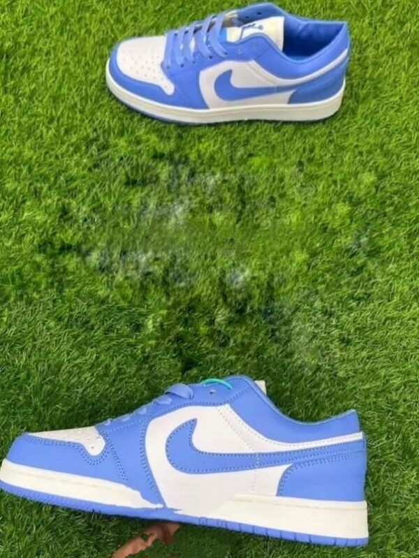 Sky blue and white low-top sneakers placed on green artificial grass, with one shoe positioned flat and the other held up.