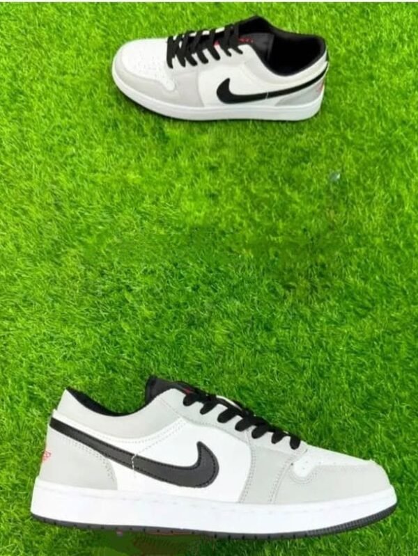 Two stylish low-top Nike sneakers in black, white, and grey placed on vibrant green grass.
